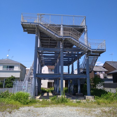 En kraftig stålställning med två trappor upp och en tom plattform ovanpå. Byggnadens enda syfte är att härbärgera ortsborna vid en naturkatastrof.