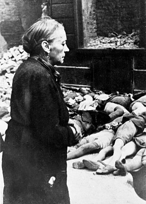 Foto på en gammal kvinna framför skolbarns lik, efter bombning av Köln 1943.