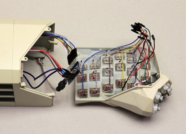 A stage in the assembly of a Concertina v0.7.0. This stage follows this one and shows two changes from it. Most importantly, the MCU has been connected to the left-hand-side key-cluster subassembly, and to the external USB port, and to the reset button. In addition, the right-hand-side key-cluster subassembly has been lined up for attachment in turn.