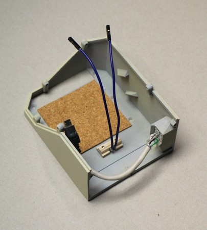 The right-hand bookend of a prototype for the v0.7.0 Concertina, with 2 mm cork glued to the inside to dampen sound, a pushbutton braced by three small pieces of plywood, and a USB port soldered to an internal pigtail cable. For a more comprehensive picture of similar lining for sound, see Concertina v0.6.0 cork lining.