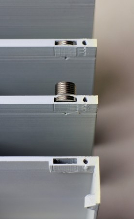 Some 10 mm × 1 mm cylinder magnets being slipped into their pockets in the central housing of a v0.7.0 Concertina. There is no practical need to align the magnetic fields, but a trivial technique for doing so is illustrated here: Move the stack of magnets down each column, slipping off enough to fill each pocket.