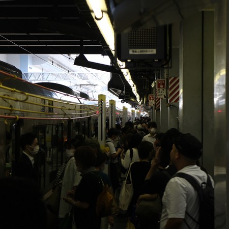 Perrong på Kyotos centralstation med passagerare överallt.