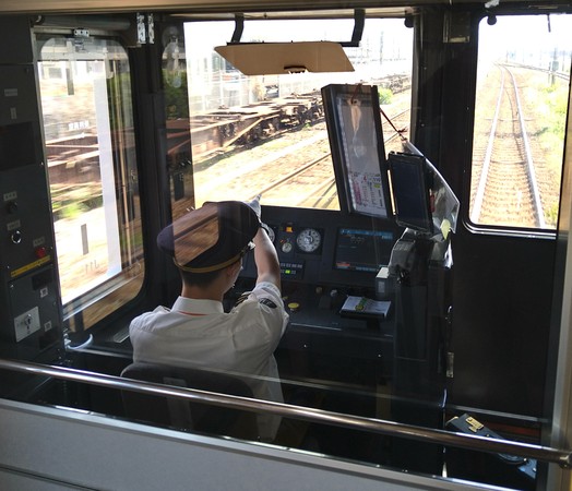 Lokföraren på väg från Maisaka till Hamamatsus centralstation pekar på positionsangivelser längs med spåret och uttalar, ohörd, vad han ser och gör. Detta kallas [pointing and calling](https://en.m.wikipedia.org/wiki/Pointing_and_calling). Han har sitt fickur i ett särskilt fack mitt på instrumentbrädan som en del av säkerhetsrutinen.