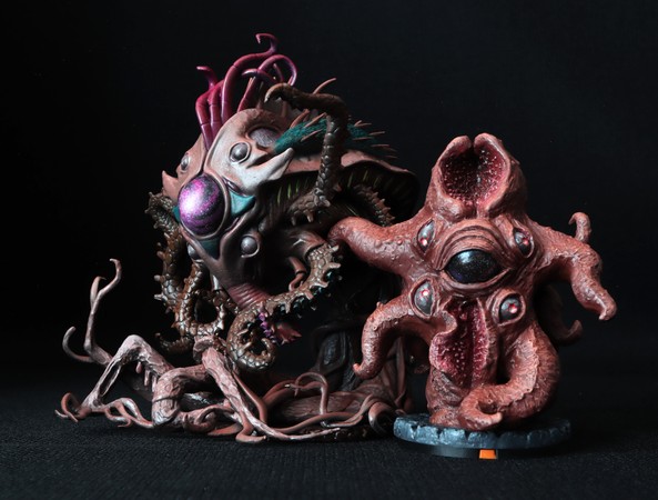 The digitally sculpted playable-faction version is on the left and the analogue non-playable faction version on the right. There is a family resemblance.